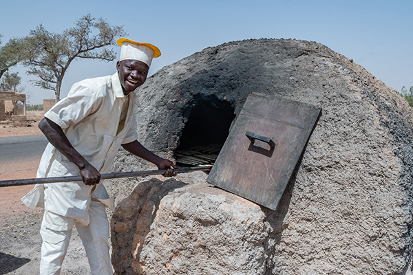 Gaston uit Burkina Faso doet brood in een oven.