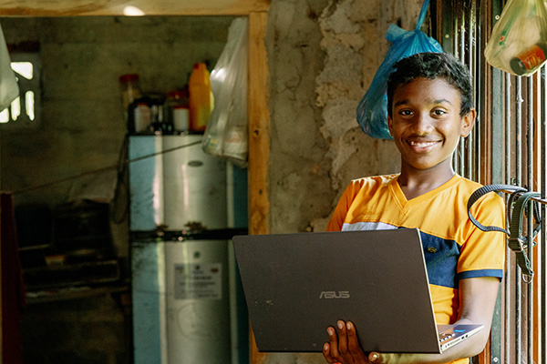 Kalana uit Sri Lanka met een laptop in zijn huis.