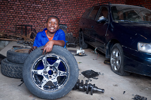 Automonteur Senga uit Rwanda poseert met een autoband.