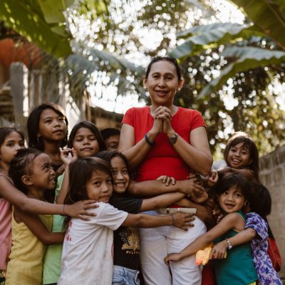 Een groep kinderen omhelst Precy Toreon, directeur van een Compassion-project op de Filipijnen.