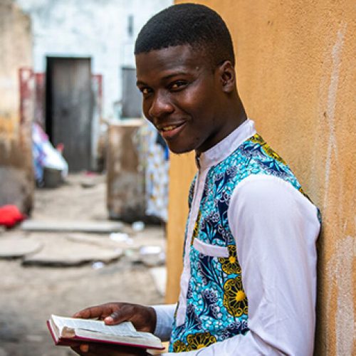 Yves uit Togo staat met zijn Bijbel in zijn hand.