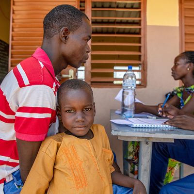 Abdias leunt tegen zijn vader aan bij de inschrijftafel van het Compassion-project.