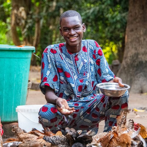 Esaïe uit Togo voert de kippen.
