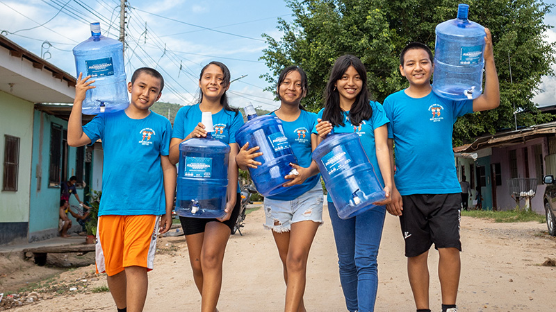 Kinderen dragen jerrycans met water in Peru. 