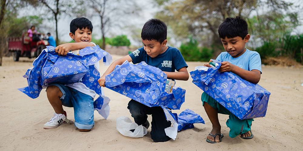 Thiago, Asael en Elias uit Peru scheuren hun kerstcadeau open. 