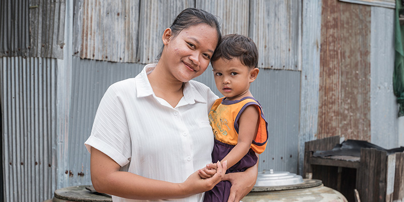 Projectmedewerker Phanna uit Cambodja heeft een kind op haar arm.