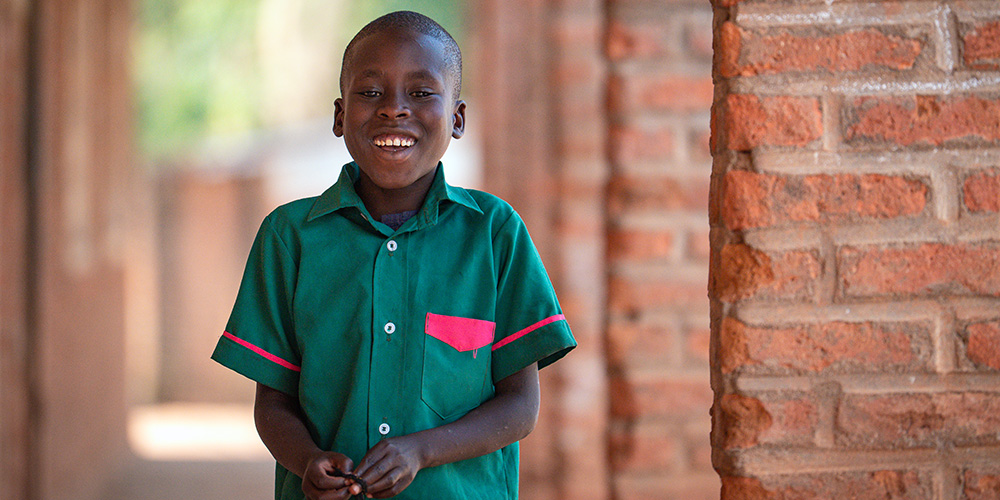 Kelvin uit Malawi kijkt lachend in de camera.